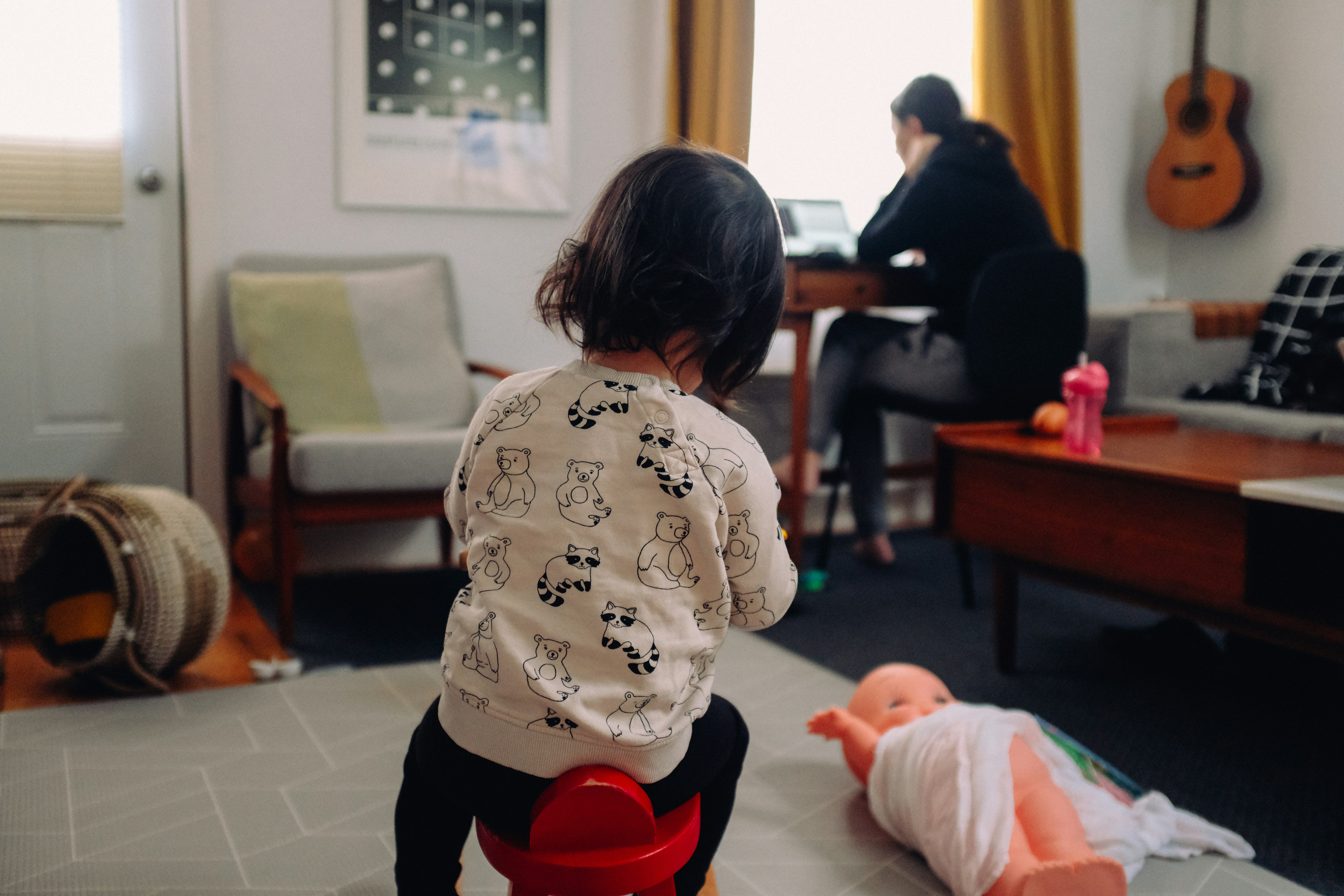 A child sits in the living room while their parent works from home