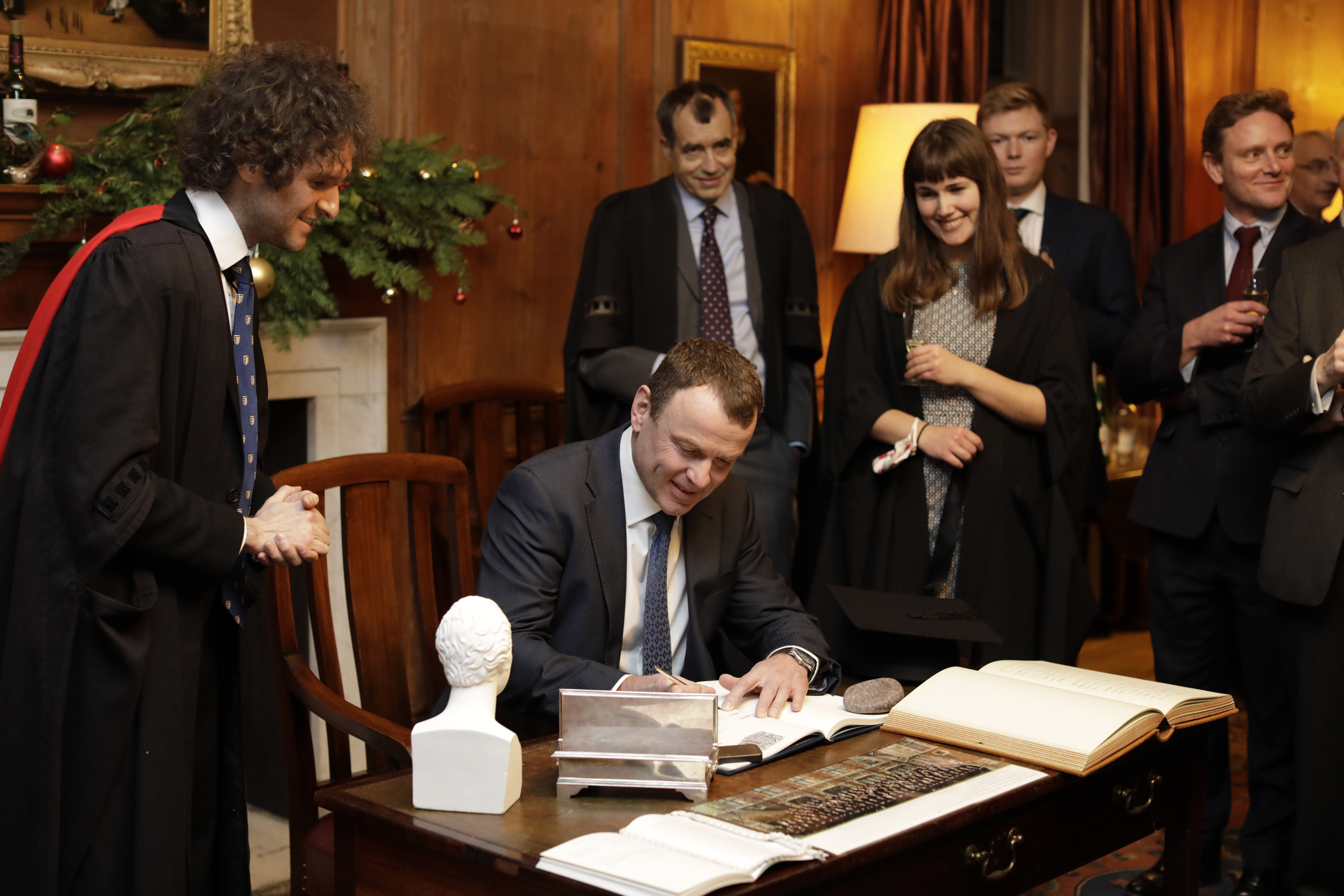 David Bateman signs the Matriculation Book, watched by the Praelector and other onlookers