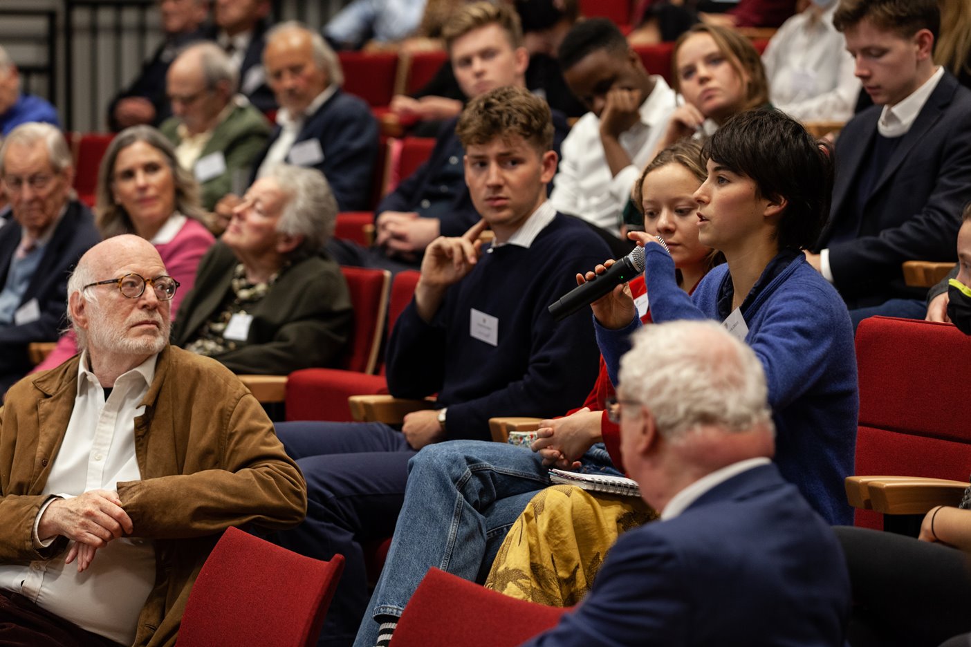 An audience member asking a question, while other audience members look on