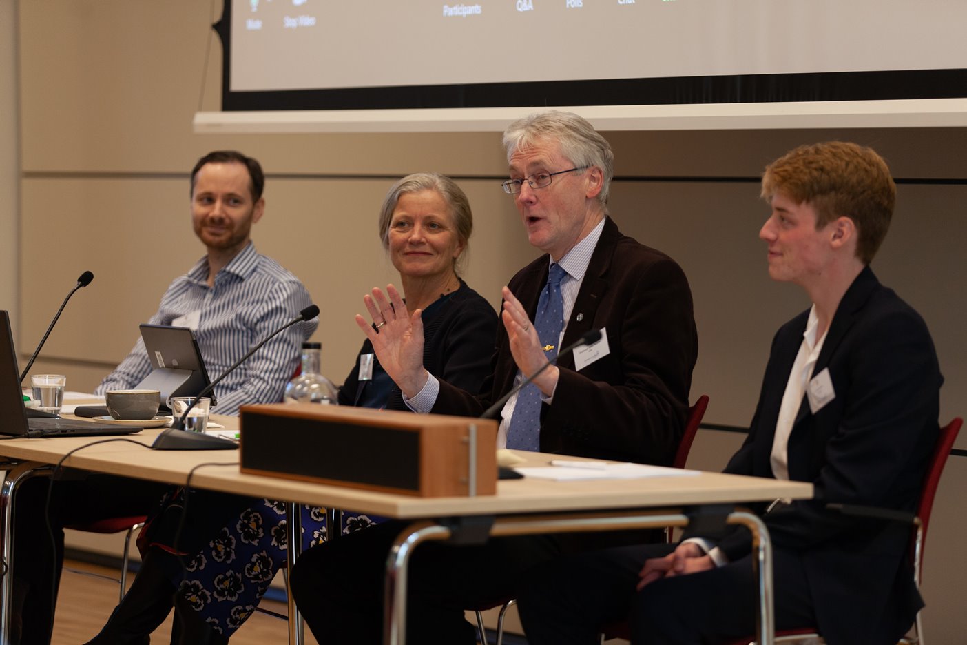 An image of the four in-person panelists. Professor Mike Hulme is speaking