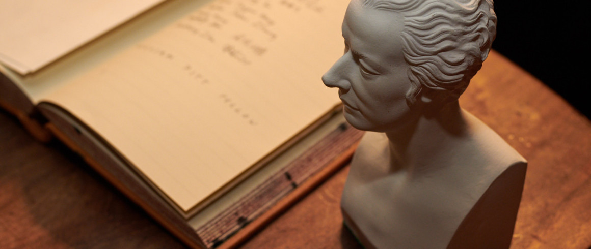 Photograph of an open book, with a head statue on the desk