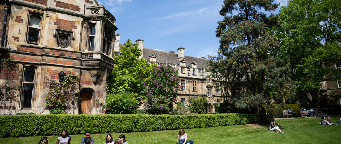 Pembroke College buildings with students sitting on grass in the foreground