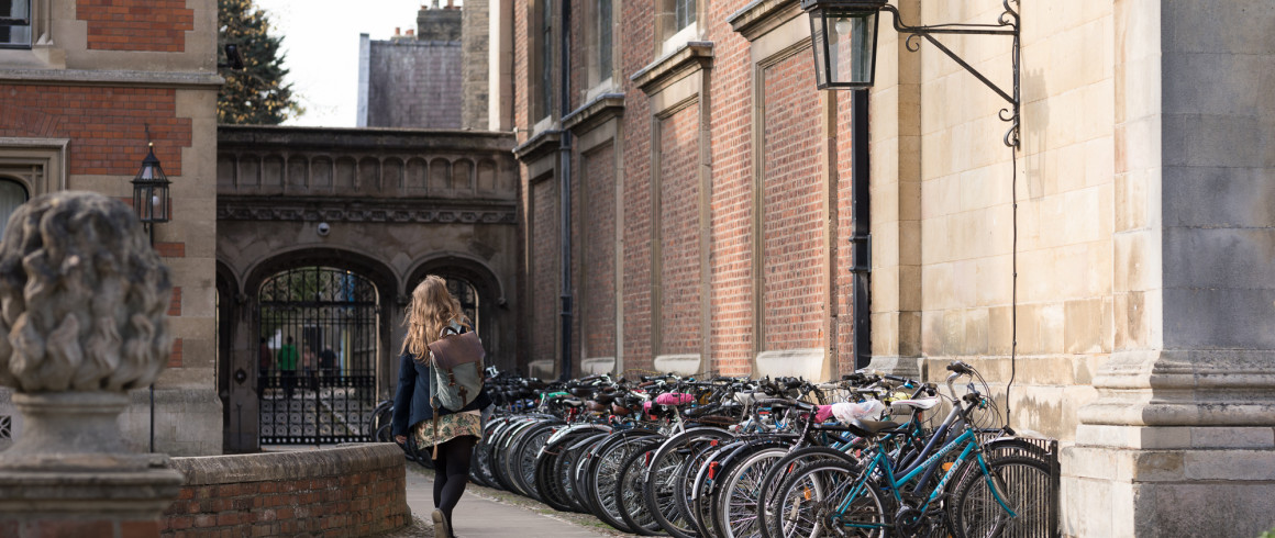 Student walking past a row of bicycles on Pembroke's ground